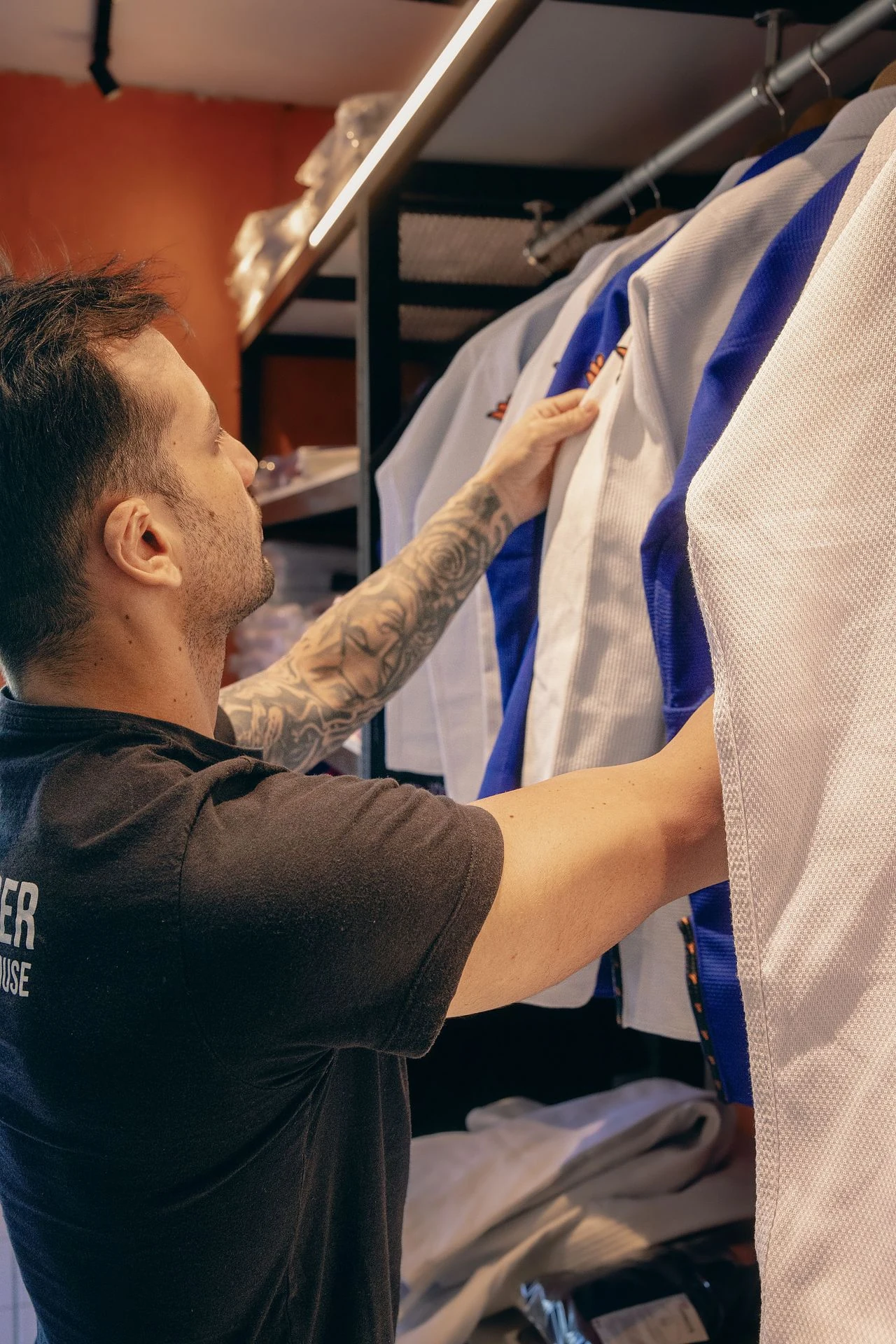 Cliente escolhendo kimonos na loja física da Combate