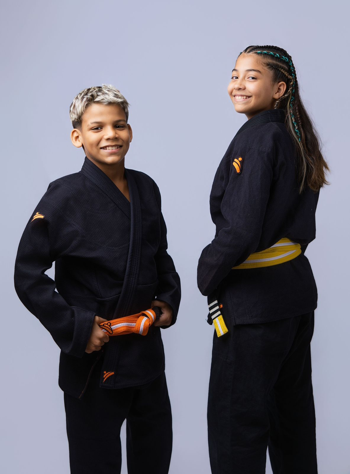 Dois jovens atletas sorrindo com kimonos pretos Combate
